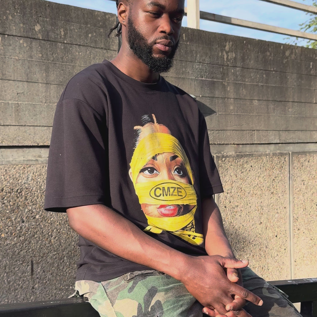 Video showing person sitting on a wall wearing a black graphic tshirt with a yellow wrap design 'CMZE'